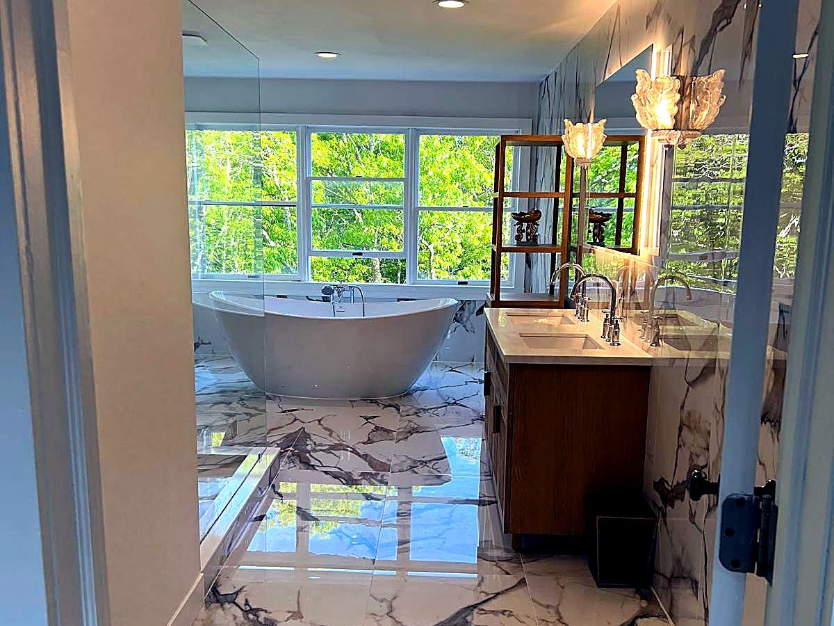 Marble bathroom with wood double vanity and sconce lighting
